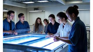 Groupe d'apprenants autour d'une machine de tissage numérique, encadrés par un expert
