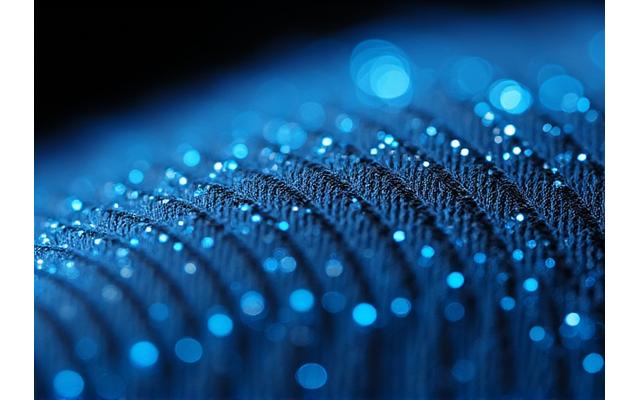Gros plan sur un textile intégrant des fibres optiques lumineuses et des micro-capteurs, démontrant la technologie de tissage interactif d'Artisanat Pixel.